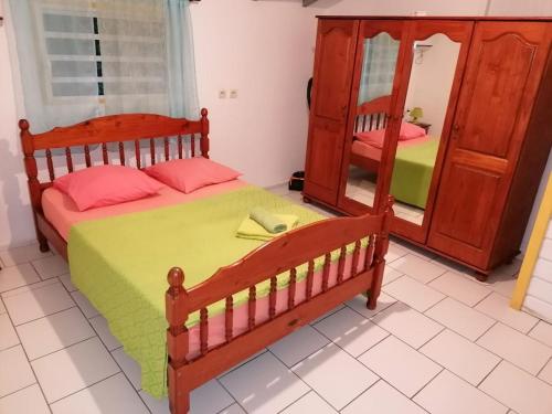 1 dormitorio con cama de madera y espejo en Résidence BLEUE DE MER en Deshaies
