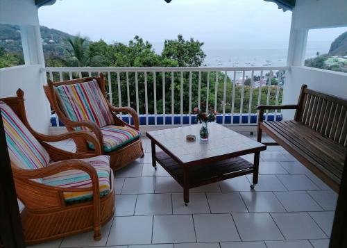 a porch with chairs and a coffee table on a balcony at Résidence BLEUE DE MER in Deshaies