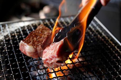 dos piezas de carne están cocinando en una parrilla en Super Hydrogen Rich Spa Yado Kanzan, en Minakami