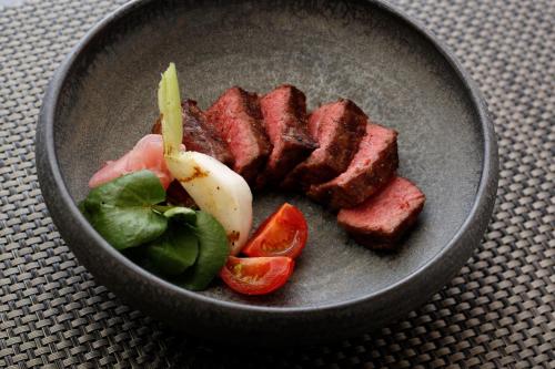 a bowl of food with meat and vegetables on a table at Super Hydrogen Rich Spa Yado Kanzan in Minakami