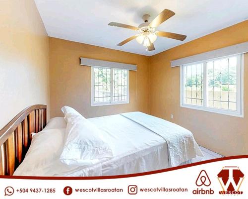a bedroom with a bed with a ceiling fan at Wescot Villas Comfort in Roatán