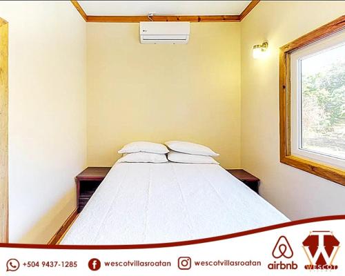 um quarto com uma cama com duas almofadas e uma janela em Wescot Villas Sky View em Roatan
