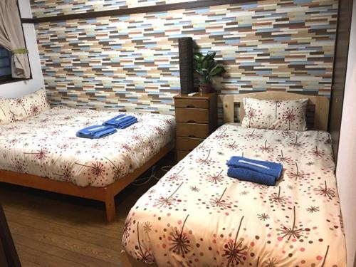 een slaapkamer met 2 bedden en blauwe handdoeken bij Cozy Family room KY apartment in Naha