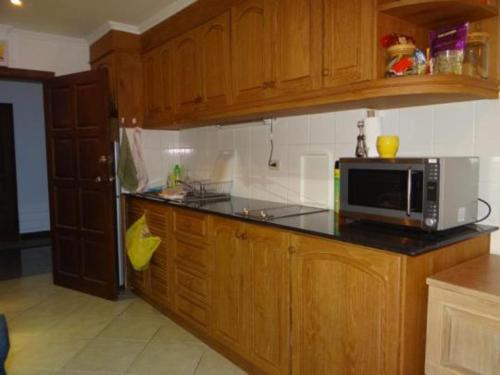 una cocina con armarios de madera y microondas en una encimera en View Talay resort 5c 116 minimum stay 29 nights, en Pattaya South
