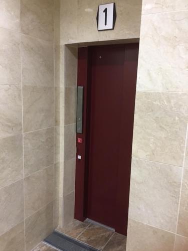 a brown door in a wall with a clock on it at Chura Gahna House Tsubogawa Naha in Naha