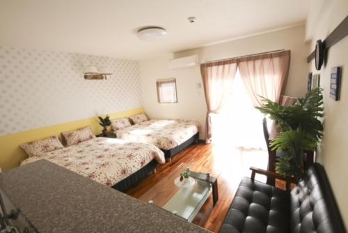 a living room with two beds and a couch at Chura Gahna House Tsubogawa Naha in Naha