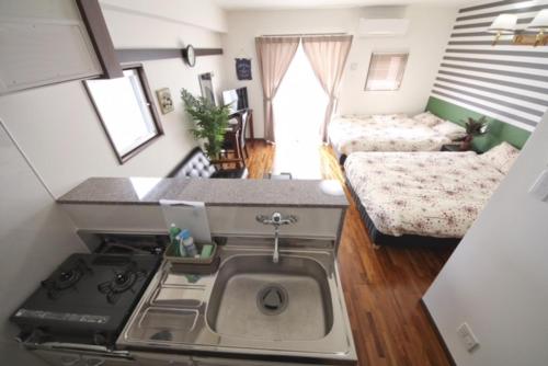 a kitchen with a sink and a stove in a room at Chura Gahna House Tsubogawa Naha in Naha