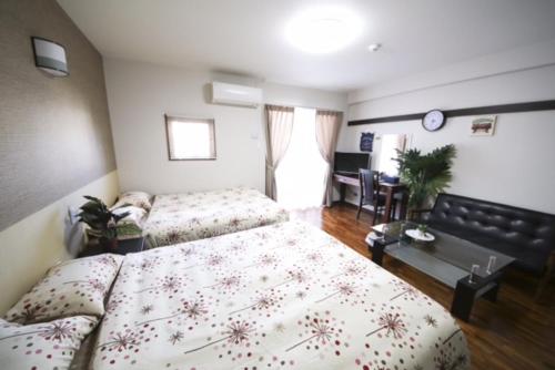 a bedroom with two beds and a desk in a room at Chura Gahna House Tsubogawa Naha in Naha