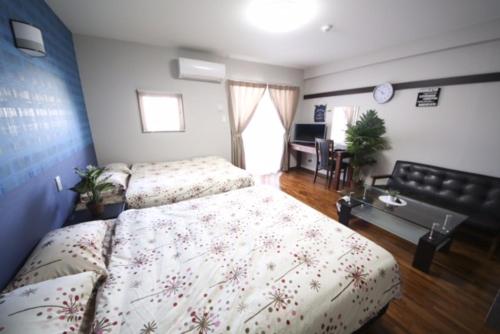 a bedroom with two beds and a desk in it at Chura Gahna House Tsubogawa Naha in Naha
