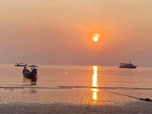 龜島的住宿－Silver Sands Resort - Koh Tao，日落时分两人在海滩上乘船
