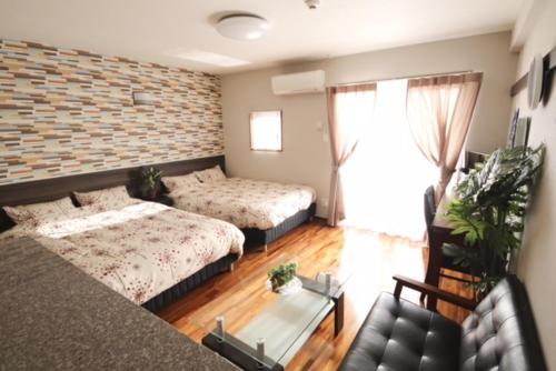a living room with two beds and a couch at Chura Gahna House Tsubogawa Naha in Naha