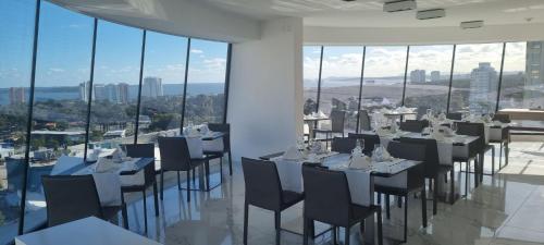 uma sala de jantar com mesas, cadeiras e janelas em Don Hotel em Punta del Este