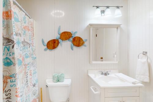 ein Badezimmer mit einem Waschbecken, einem WC und einem Spiegel in der Unterkunft Sandy Feet Retreat KDH127 in Kill Devil Hills