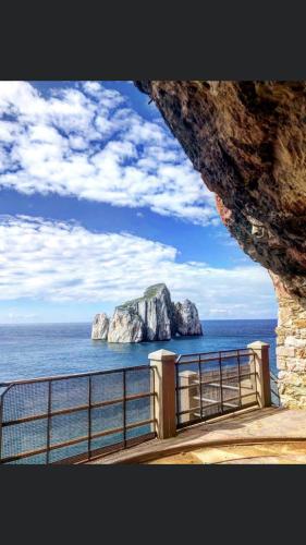 a large rock in the ocean next to a fence at le mura in Iglesias