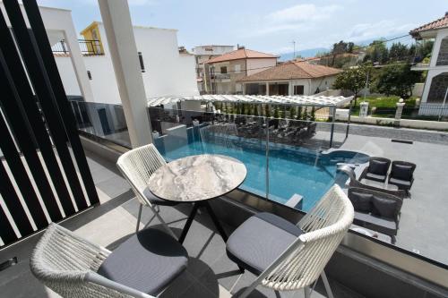 a balcony with a table and chairs and a swimming pool at Aeonian Luxury Suites Asprovalta, Adults Only & Kids 12 Plus in Asprovalta
