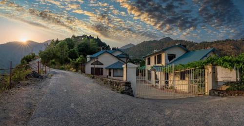 a dirt road with houses and a fence with the sunset at Karinya Villas in Nainital