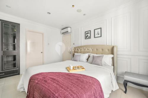 a white bedroom with a bed with a tray on it at Palais by Kozystay - Thamrin in Jakarta