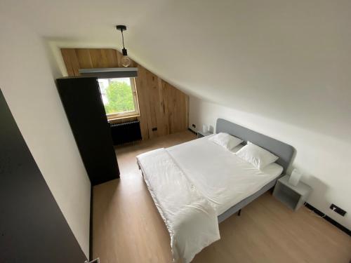 um quarto com uma cama com lençóis brancos e uma janela em La Villa 1968 em Bütgenbach