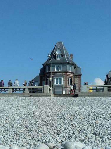 a house on the beach with people standing around it at LES EMBRUNS in Fécamp