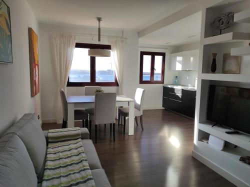 sala de estar con sofá y mesa de comedor en ATALAYA SUNSET terrazza panoramica privata con vista al mare, en Corralejo