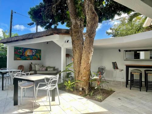 um pátio com uma mesa e cadeiras ao lado de uma árvore em Guest House et Restaurant Sous le Badamier em Grand Baie