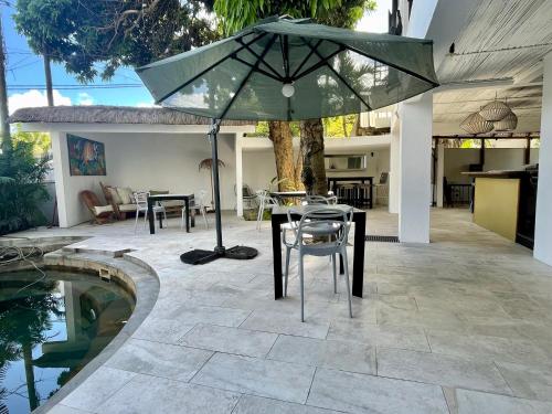 a patio with a table and an umbrella next to a pool at Cosy Guest House Sous le Badamier in Grand Baie