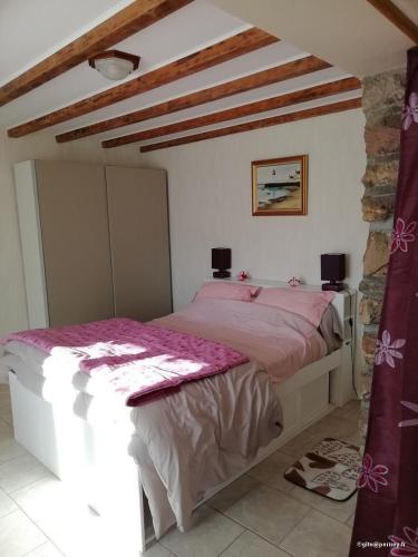 Cette chambre comprend un lit avec des draps roses et un mur en pierre. dans l'établissement Gîte rural Les Maires d'Avaux, à Saint-Bresson