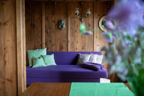 Chalet Abnona في فيدين: أريكة أرجوانية في غرفة مع جدران خشبية