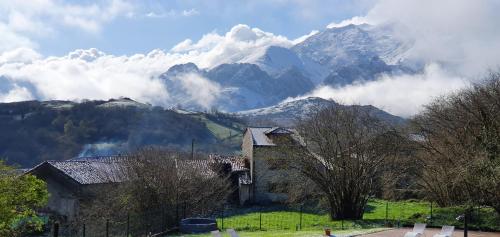 a mountain obscured by clouds with a house and trees at Refugio del Cares in Ortiguero