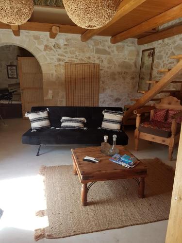 a living room with a black couch and a coffee table at Old stone villa in Apokoronas Villa Nostalgia Kreta in Fílippos