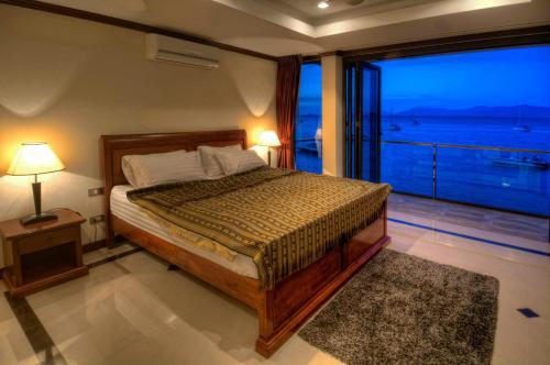 a bedroom with a bed with a view of the ocean at Emerald Beach-Front Apartments Fishermans Village in Koh Samui 