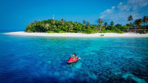 a person in a kayak in the ocean with an island at Sabba Beach Suite , Fodhdhoo - Maldives in Velidhoo