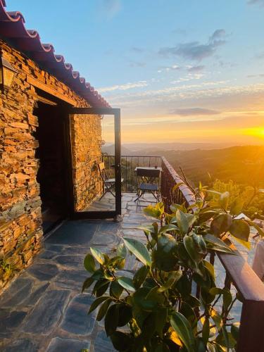 a view from the deck of a house with a sunset at Bela Vista Alqueve - traditional stone house and private pool in Arganil