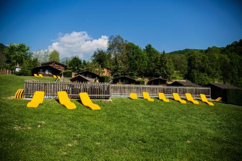 una fila de bancos amarillos sentados en el césped en Stura River Village RAFTING, en Gaiola