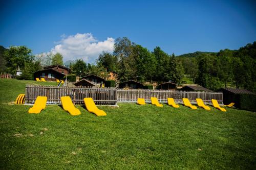 a row of yellow benches sitting in the grass at Stura River Village RAFTING in Gaiola