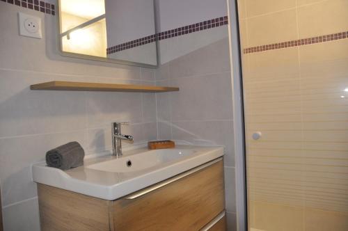 ein Bad mit einem Waschbecken und einem Spiegel in der Unterkunft Studio avec terrasse privative et piscine in Grillon