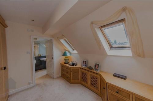 een zolderkamer met een raam en een houten dressoir bij Morning Glory in Bolton