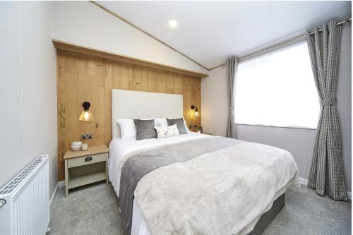 Un dormitorio con una cama grande y una ventana en Luxury Lodge - Hoburne Devon Bay, en Paignton