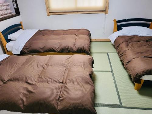 dos camas sentadas una al lado de la otra en una habitación en Hakuba Inn Bloom en Hakuba