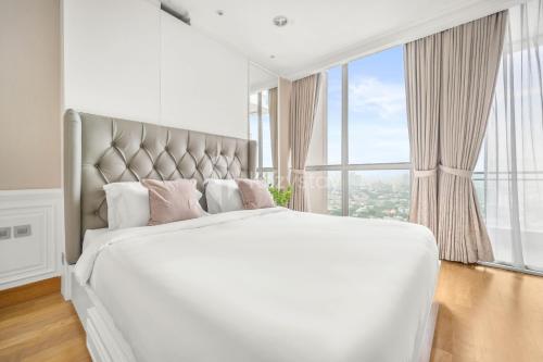 una camera da letto con un grande letto bianco con una grande finestra di BLANC by Kozystay - 1BR Apartment in SCBD a Giacarta
