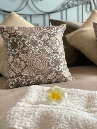 a pillow and a flower on top of a bed at La Pomelia B&b Sofia in Trappitello
