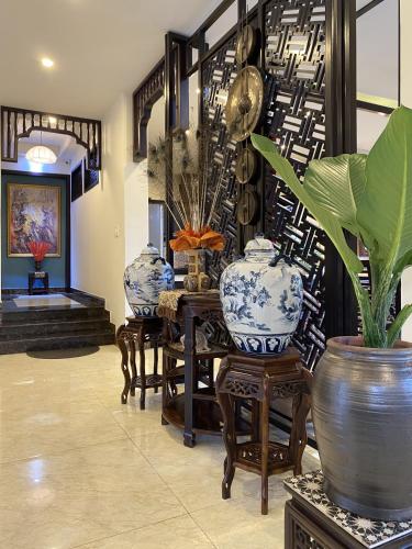 a room with three blue and white vases and chairs at The Quin Riverside Villa in Hoi An