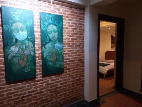 a brick wall with three paintings on it at TARA ART HOUSE in Pātan