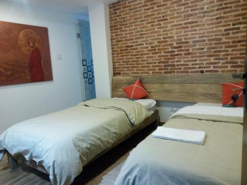 two beds in a room with a brick wall at TARA ART HOUSE in Pātan