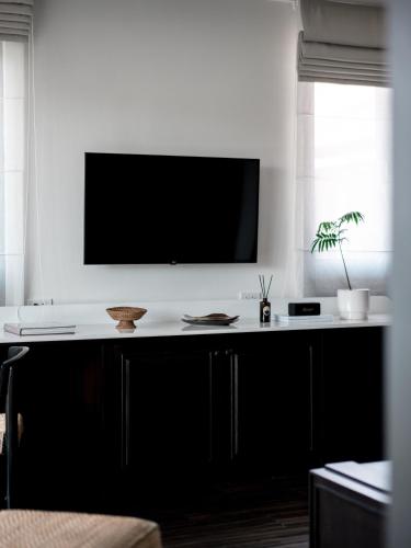 a living room with a tv on a white wall at Burirattana Hotel-An Adults Only Hotel in Chiang Mai