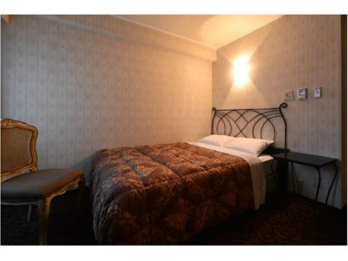 a bedroom with a large bed and a chair at Sakura Fleur Aoyama in Tokyo