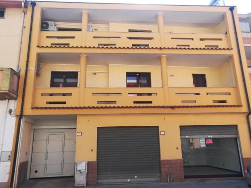 un edificio amarillo con dos puertas de garaje delante de él en Guesthouse Loru, en Sestu
