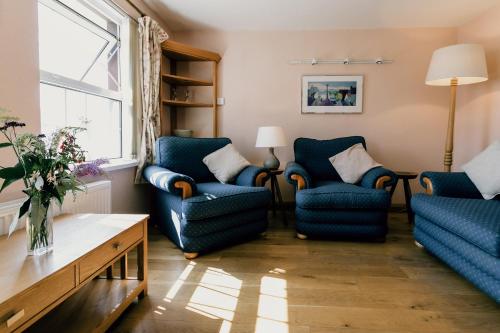 a living room with blue chairs and a table at Galwad y Mor in St. Davids