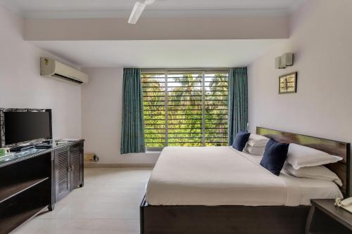 a bedroom with a large bed and a large window at Arotel Rooms & Suites in Calangute