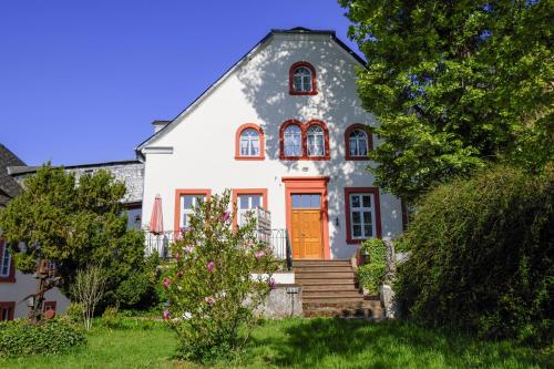 a white house with an orange door and stairs at Hotel Klostermühle Siebenborn in Maring-Noviand
